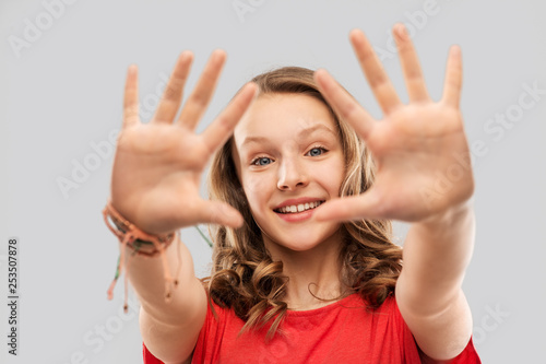 people concept - smiling teenage girl with long hair in red t-shirt giving high five over grey background