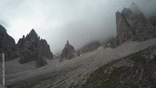 Drone aerial video on the spectacular rocks of Tofana in the Dolomites of Cortina D’Ampezzo in a cloudy moment that produce a special atmosphere. photo