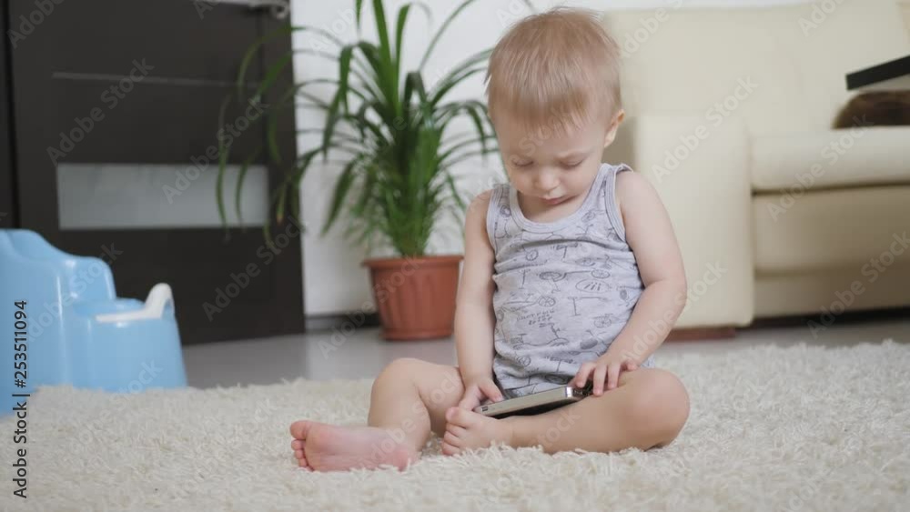 Little boy is watching cartoons on smartphone on the floor at home, lifestyle. Little boy is watching cartoons on smartphone on the floor at home, lifestyle.