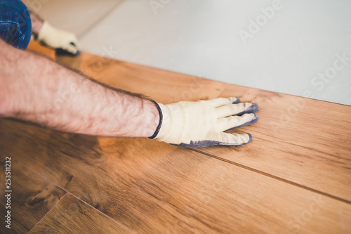 The builder is engaged in laying laminate in the room - repair and finishing work
