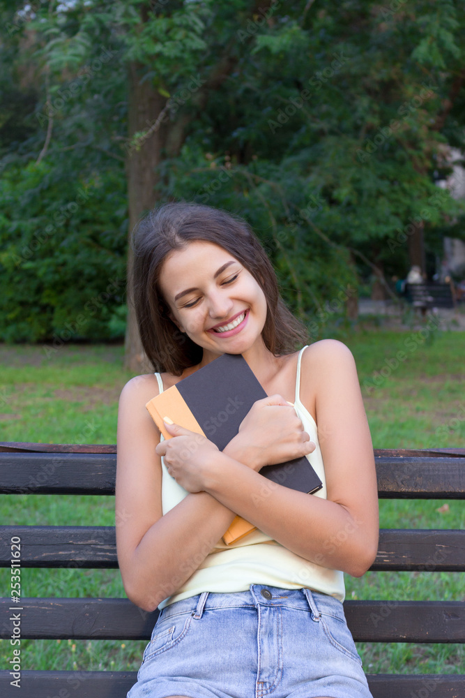 Young girl is hugging her favourite textbook in the park Young girl is hugging her favourite textbook in the park