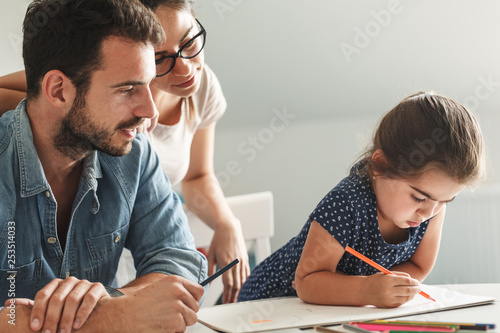 Father and mother teach daughter to draw.They sitting in living room.Education and family concept.