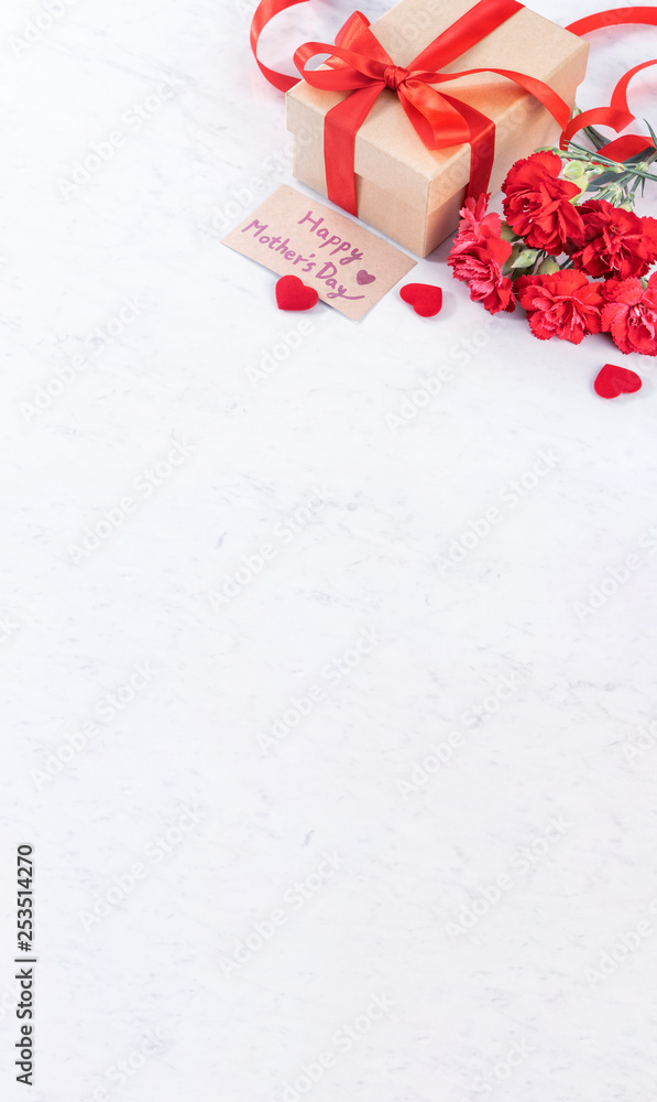 May mothers day concept handmade giftbox idea wishes photography - Beautiful blooming carnations with red ribbon bow box isolated on modern marble desk, close up, copy space, mock up
