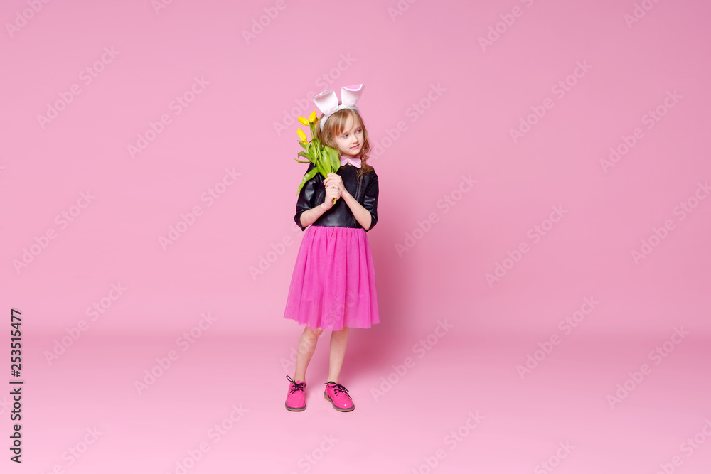 Cheerful girl with a bouquet of yellow tulips on a pink background. Holidays, fashion and red concept. Cheerful girl with a bouquet of yellow tulips on a pink background. Holidays, fashion and red concept.