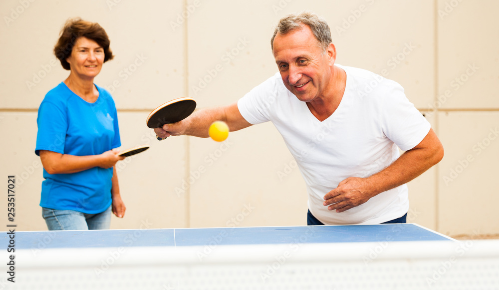 Fototapeta premium Happy mature man and woman playing table tennis