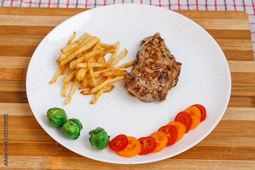 Beefsteak with vegetables and french fries on a white plate