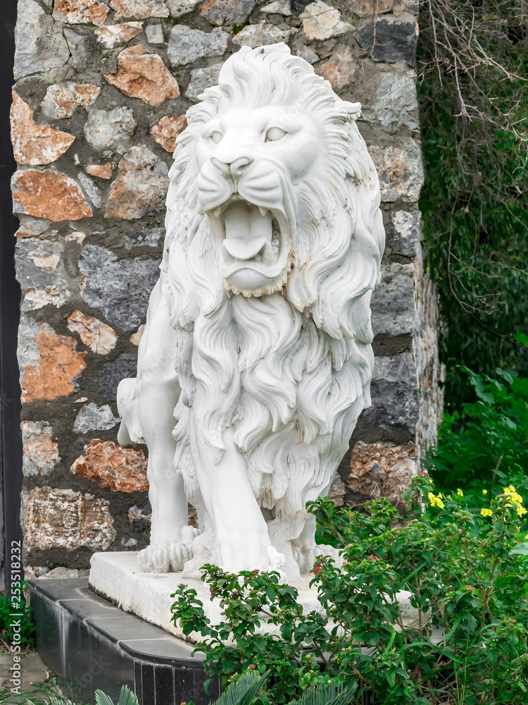 City sculpture of a white lion with open mouth at the entrance. Local landmark. Front view