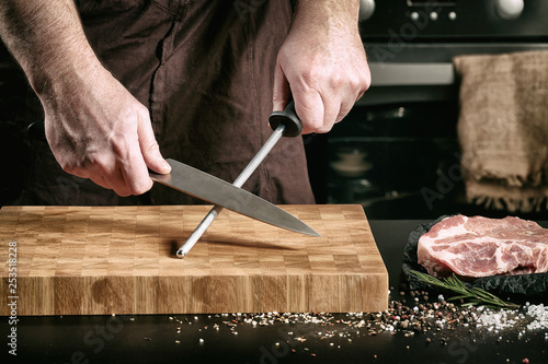Closeup of male chef hands sharpen a big chef's knife photo
