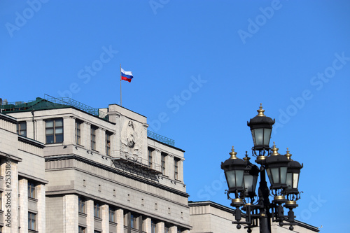 Russian flag on the Parliament building in Moscow against blue sky. Russian authority, facade of State Duma of Russia with soviet coat of arms © Oleg