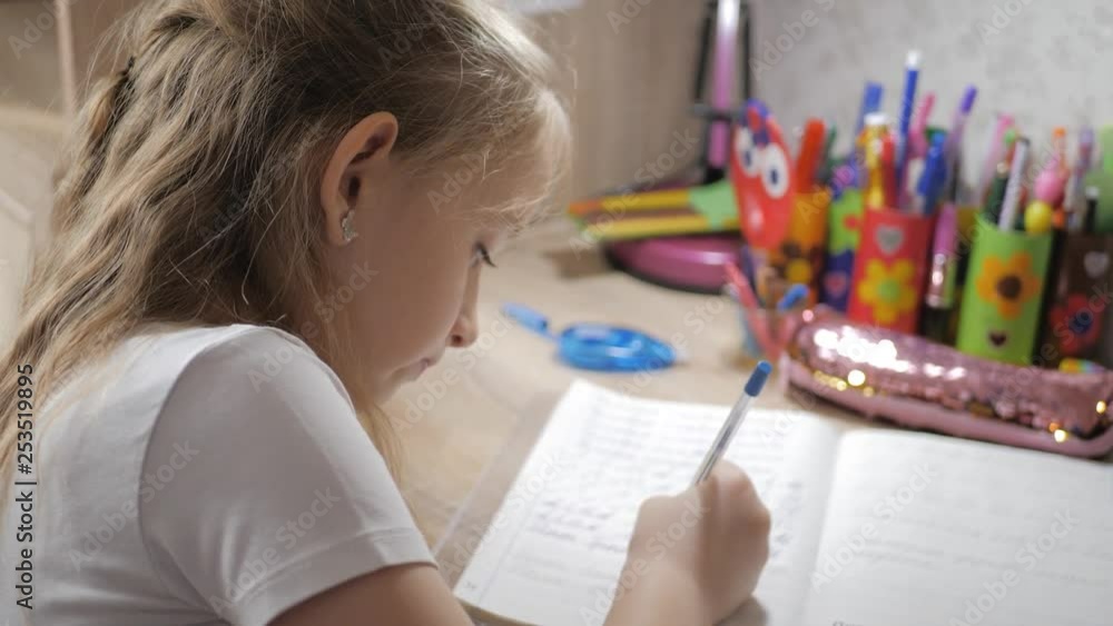 Young girl makes its homework at on the table under the light of a lamp. Creative hobby of little princess. lifestyle of talented people. Young girl makes its homework at on the table under the light of a lamp. Creative hobby of little princess. lifestyle of talented people.