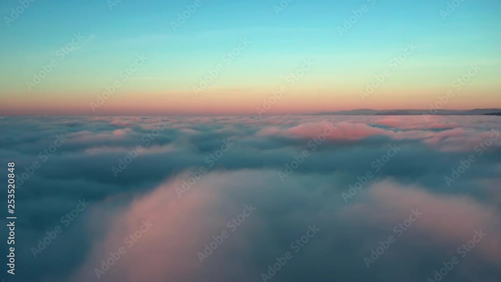 Aerial rising pan shot ascending above fluffy clouds that are being illuminated by a sunset. Aerial rising pan shot ascending above fluffy clouds that are being illuminated by a sunset.