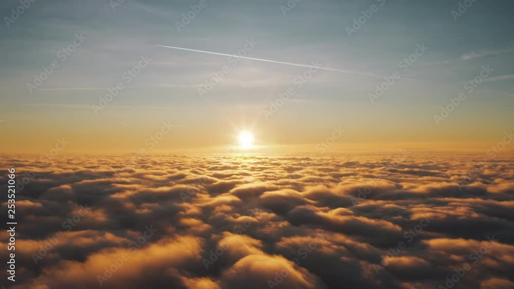 High aerial view above fluffy clouds that are illuminated by a center frame sunset, descending. High aerial view above fluffy clouds that are illuminated by a center frame sunset, descending.