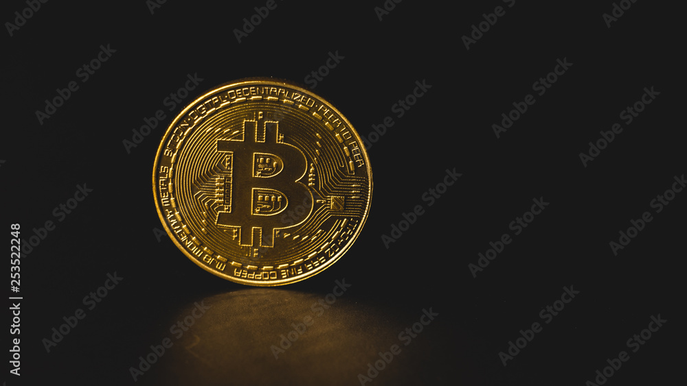 Close up view of bitcoin concept on black background with copy space on right. Golden coin glowing in soft light. Close up view of bitcoin concept on black background with copy space on right. Golden coin glowing in soft light.