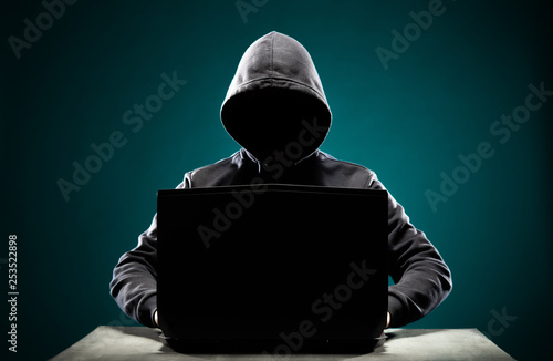 Computer hacker in hoodie. Obscured dark face. Data thief, internet fraud, darknet and cyber security concept. photo