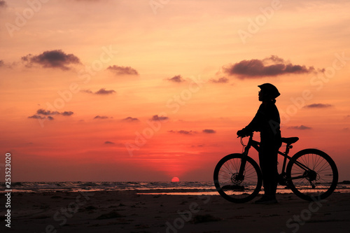 Silhouette of woman and bicycle at sunset background