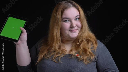 Closeup shoot ofyoung overweight caucasian female using the tablet and showing green chroma screen to camera and smiling photo