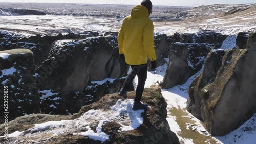 Young Traveler walking down steep path at Fjadrargljufur Canyon in Winter photo