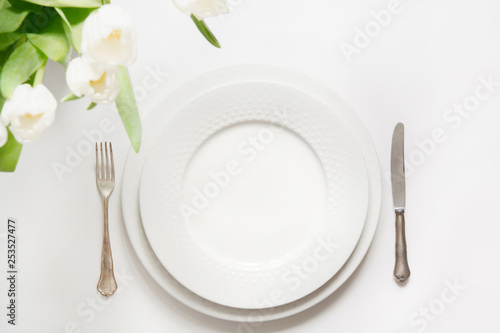 Easter dinner. Table setting with white tulip on white table.