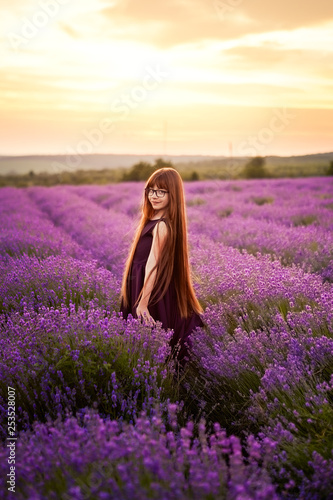 Portrait of a beautiful young girl in a violet dress with a bouquet of lavender in the rays of the setting sun