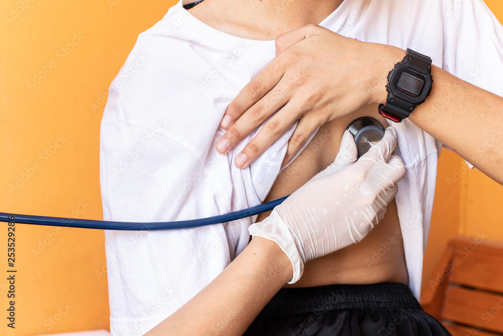 Fototapeta premium Doctor examining heartbeat of boys with stethoscope.