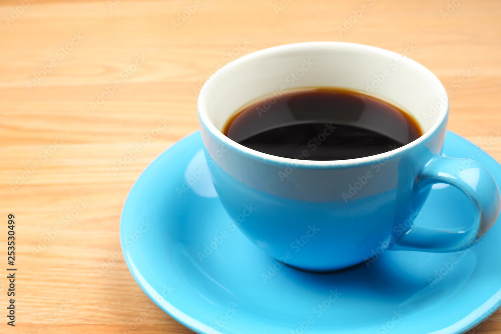Black coffee in blue cup on brown wooden table background
