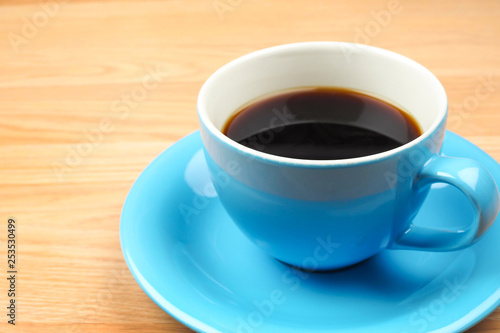 Black coffee in blue cup on brown wooden table background