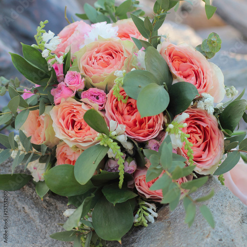 Bridal bouquet lying on the stones. Wedding bouquet of peach roses by David Austin   single-head pink rose aqua  eucalyptus  ruscus  gypsophila