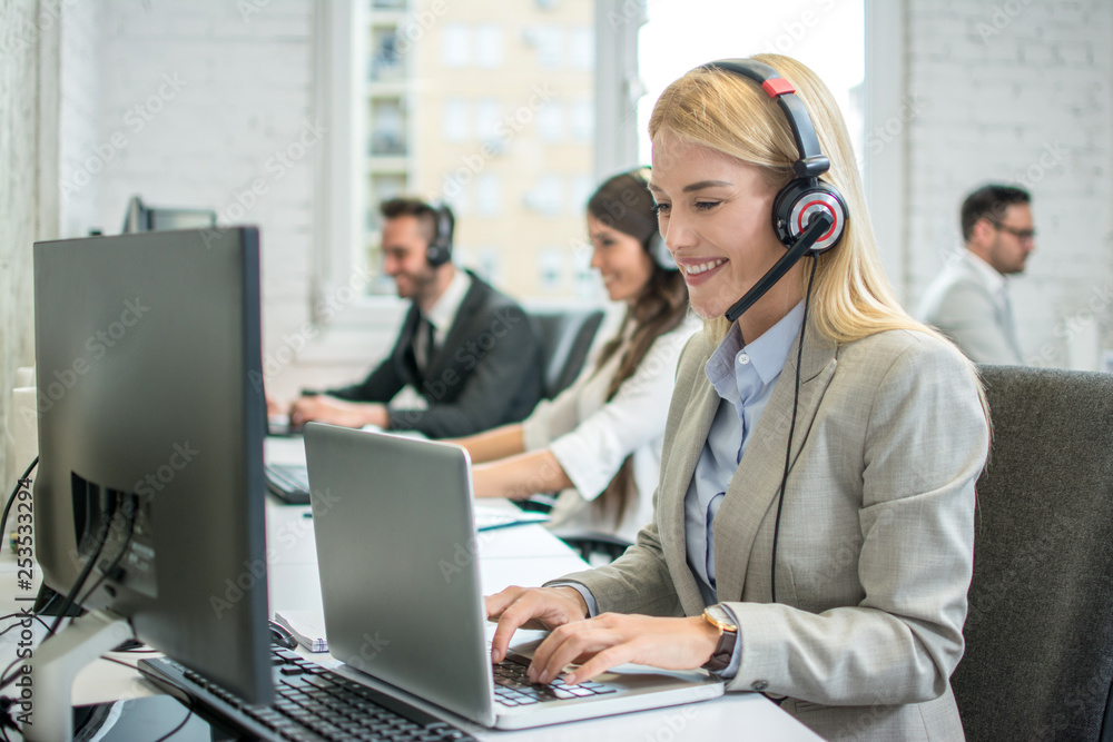 Portrait of smiling blonde haired operator woman working on laptop in call center. Portrait of smiling blonde haired operator woman working on laptop in call center.