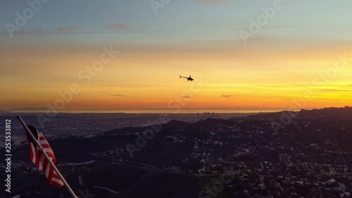 Helicopter Flies past camera towards Sunset with American Flag (USA) Flying In The Wind photo