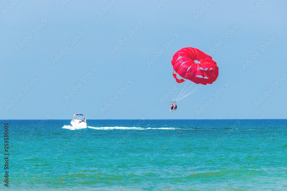 Tourists have fun, parachuting behind a boat, parasailing Tourists have fun, parachuting behind a boat, parasailing