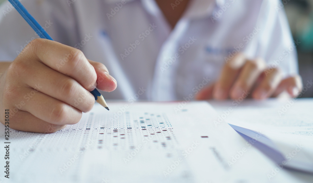 Answers to the questions.Students hand holding pencil writing selected choice on answer sheets and.students testing doing examination.Exam carbon paper computer sheet. Answers to the questions.Students hand holding pencil writing selected choice on answer sheets and.students testing doing examination.Exam carbon paper computer sheet.