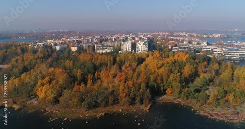 Aerial, tracking, drone shot, sideways above the sea, with a view over Lauttasaari area, on a sunny, fall day, in Helsinki city, in Finland photo