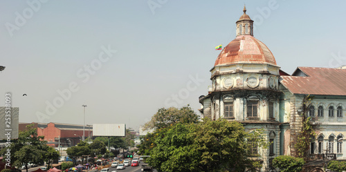 panorama of a busy street intersection in central Yangon, Myanmar, Southeast Asia, with traffic and old deteriorating British colonial buildings