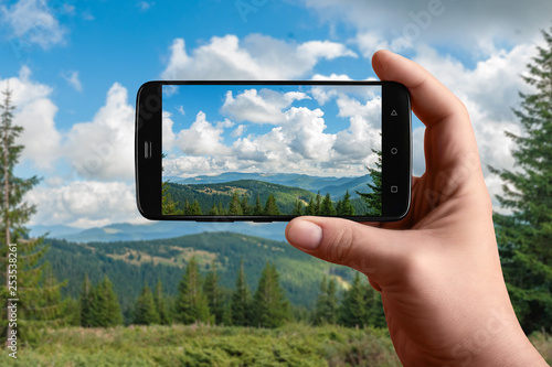 Smartphone in hand photographs nature on the screen. Photos of the mountain panorama for posting on social networks.
