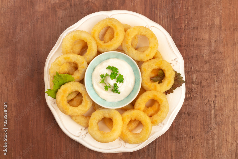 Squid rings with mayonnaise and salad leaves on a dark rustic wooden background with copy space Squid rings with mayonnaise and salad leaves on a dark rustic wooden background with copy space