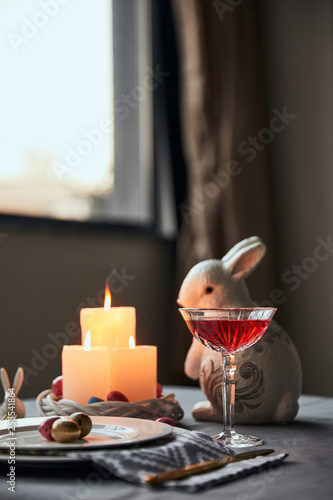 selective focus of plates with eggs, wine in crystal glass and decorative rabbit  on table at home