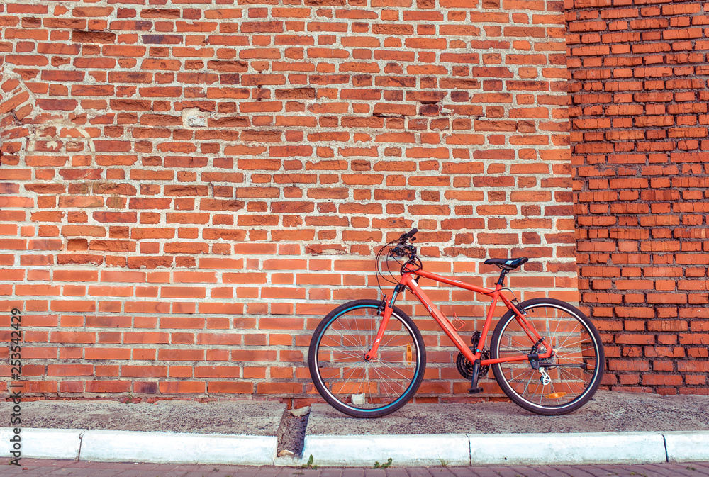 Red sports bike stands on a brick wall background. Free space for text. Free space, the concept of a healthy lifestyle in city. Parking and fitness and sports left in the city. Red sports bike stands on a brick wall background. Free space for text. Free space, the concept of a healthy lifestyle in city. Parking and fitness and sports left in the city.
