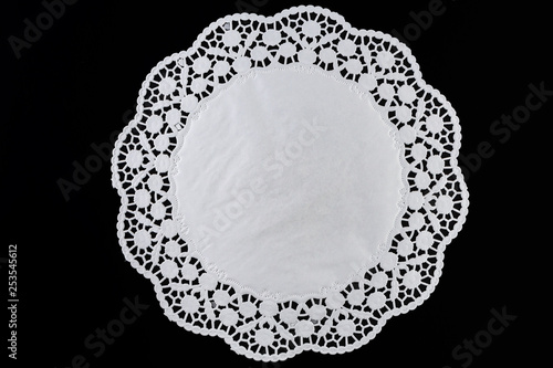 White paper round lace doily, on black background. photo