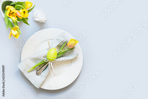 Easter dinner. Table setting with yellow tulip on table. Top view.