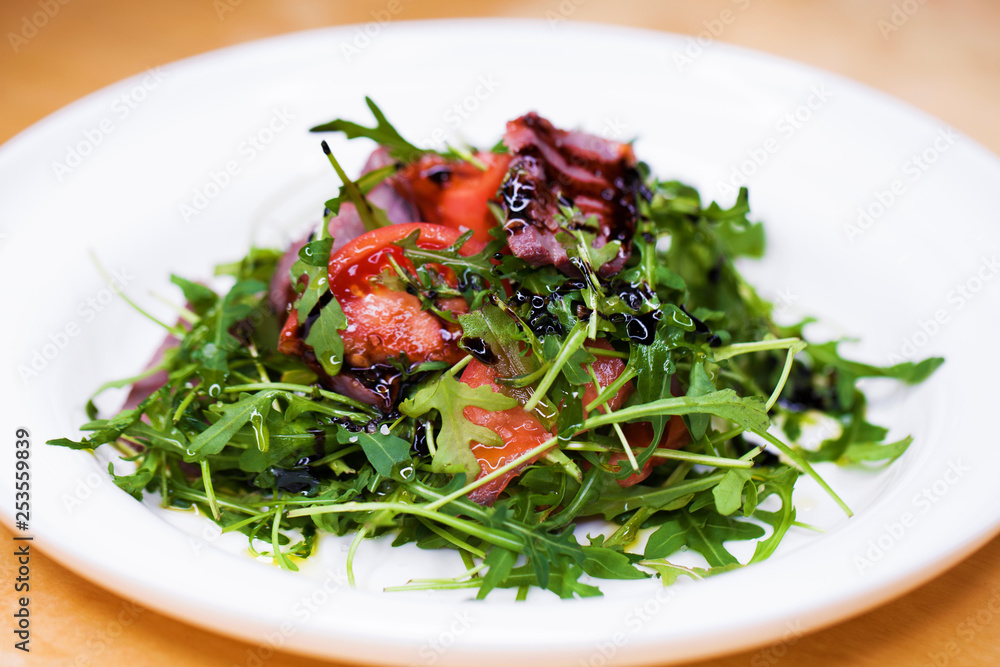 Salad with pieces of marbled beef and arugula on a white plate Salad with pieces of marbled beef and arugula on a white plate