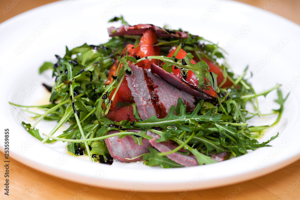 Salad with pieces of marbled beef and arugula on a white plate Salad with pieces of marbled beef and arugula on a white plate