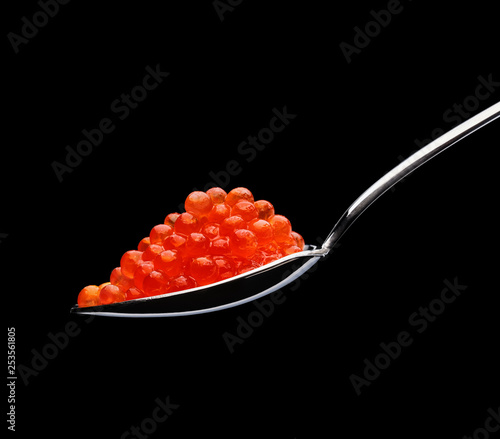 Steel spoon with red caviar on a black background. Russian delicacy