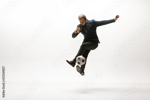 Businessman with a cup of coffee and football ball in office. Soccer freestyle. Concept of balance and agility in business. Manager perfoming tricks isolated on white studio background.