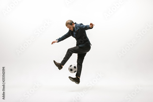 Businessman with football ball in office. Soccer freestyle. Concept of balance and agility in business. Manager perfoming tricks isolated on white studio background.