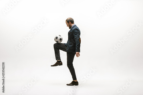 Businessman with football ball in office. Soccer freestyle. Concept of balance and agility in business. Manager perfoming tricks isolated on white studio background. © master1305