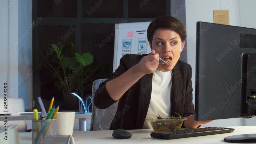 business, overwork, deadline and people concept - businesswoman with computer eating salad at night office business, overwork, deadline and people concept - businesswoman with computer eating salad at night office