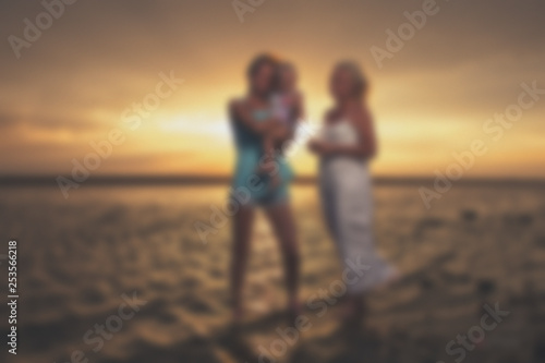 Blurred - young female homosexual lesbian family at sunset on the lake.