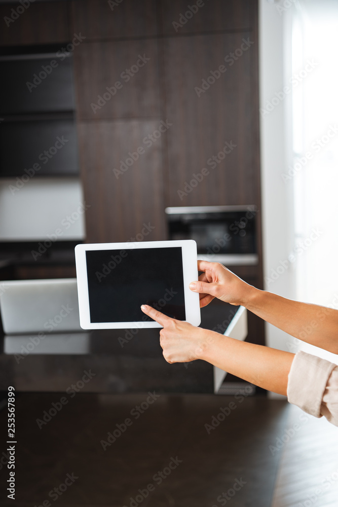 selective focus of woman pointing at blank screen of digital tablet