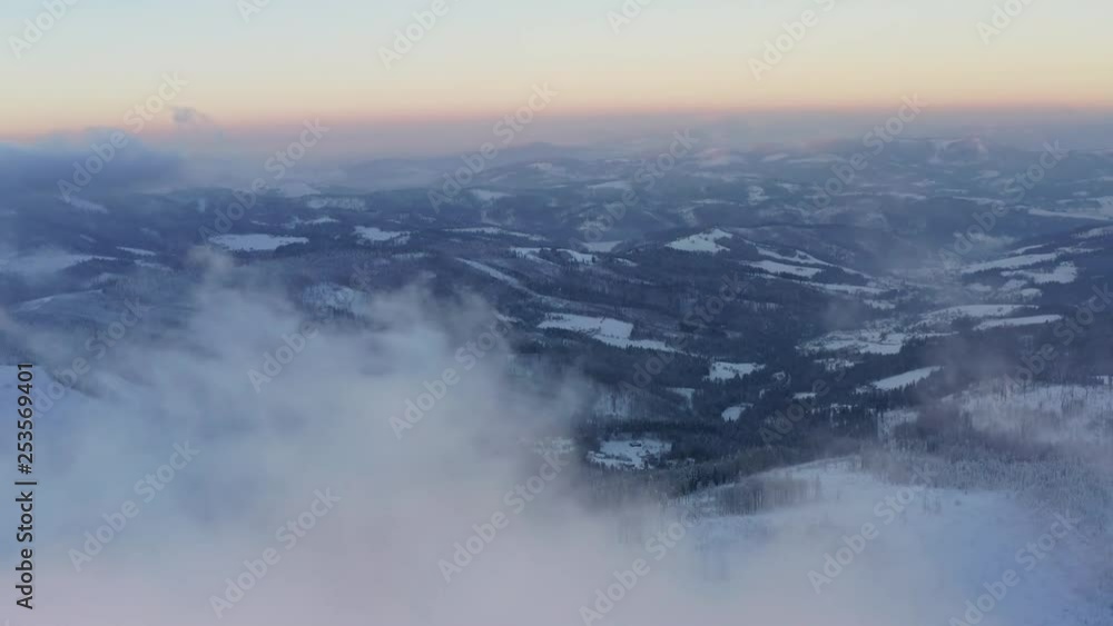 Flying along a snow covered mountains over clouds at dawn Flying along a snow covered mountains over clouds at dawn