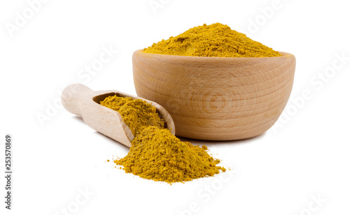 yellow curry in wooden bowl and scoop isolated on white background. Spices and food ingredients. photo